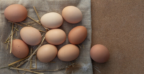 Farm eggs on burlap and straw with space for text. Rustic flat lay, top view
