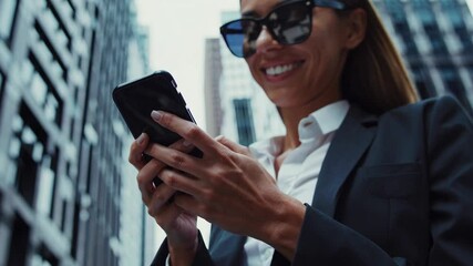 Elegant visuals of businesspeople smiling and texting on smart phones, walking through busy streets lined with corporate buildings, showcasing urban professional success - Powered by Adobe