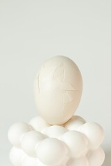 Cracked white egg placed on a modern bubble-style egg holder on isolated white background. 