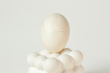 Cracked white egg placed on a modern bubble-style egg holder on isolated white background. 
