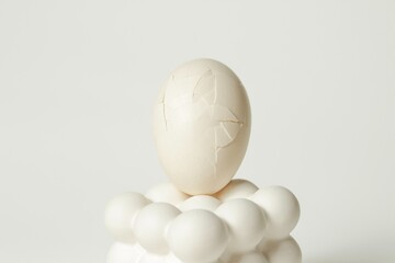 Cracked white egg placed on a modern bubble-style egg holder on isolated white background. 