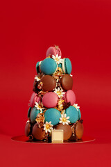 Colorful macarons forming a pyramid on red background with gold leaf decoration