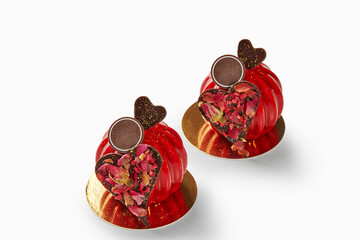 Two red mousse cakes decorated with chocolate hearts and rose petals for valentine's day