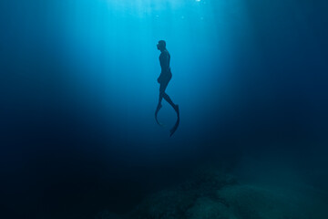 Freediver Swimming in Deep Sea With Sunrays. Young Man Diver Eploring Sea Life.