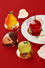Delicious fruit shaped cakes resembling apple, pear, cherry and acorn on red background