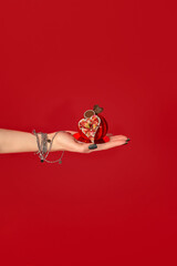 Woman hand holding red heart shaped chocolate praline for valentine's day