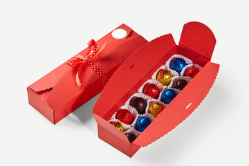 Colorful wrapped chocolate balls in red gift box with ribbon