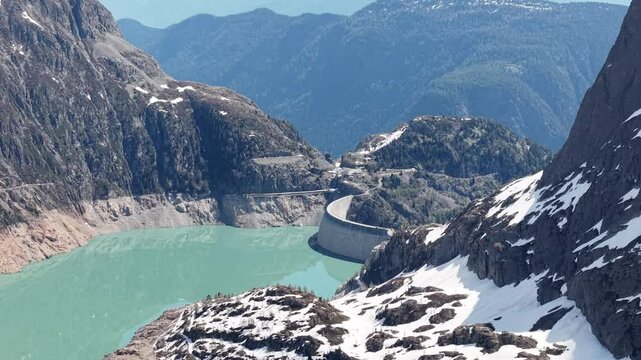 Vue a&eacute;rienne spectaculaire d&rsquo;un barrage en arc au c&oelig;ur des Alpes, entour&eacute; de neige et de montagnes rocheuses. Vid&eacute;o drone 4k 60fps
