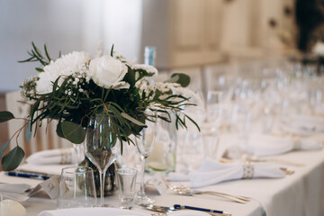 Elegant wedding banquet table decorated with white florals, glassware, and folded napkins for a sophisticated celebration.