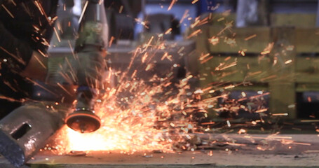 Male hand cuts off pieces of water pipe with angle grinder. Cutting of a steel with splashes of sparks at construction site. Sparks during cutting of metal angle grinder