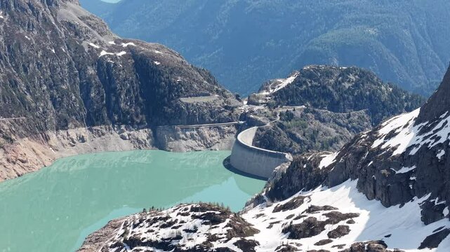 Vue a&eacute;rienne spectaculaire d&rsquo;un barrage en arc au c&oelig;ur des Alpes, entour&eacute; de neige et de montagnes rocheuses. Vid&eacute;o drone 4k 60fps
