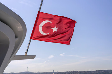 Waving red Turkish flag and a view along turquoise waters of Bosphorus Bridge
