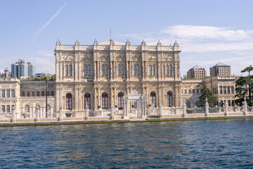Obraz premium Dolmabahce palace on waterfront of Istanbul, Turkey, seen from a yacht on the Bosphorus strait. Majestic Ottoman architecture on clear, sunny day