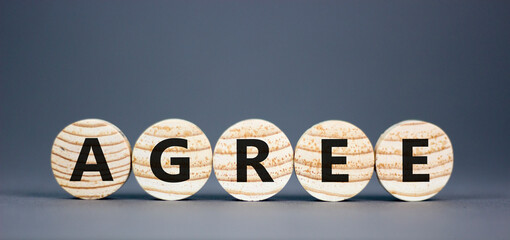 Agree symbol. Concept word Agree on beautiful wooden circles. Beautiful grey table grey background....