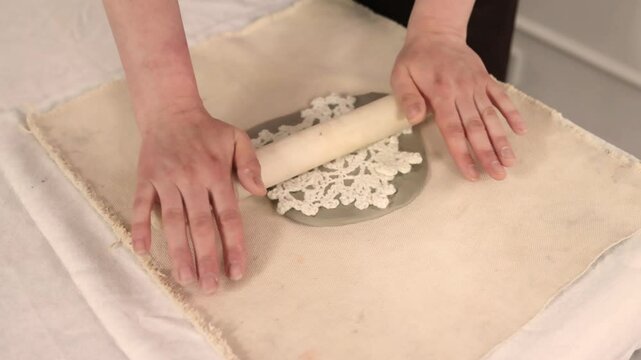 Making ceramic Christmas decor in pottery studio with snowflake stencil and pin Cozy festive