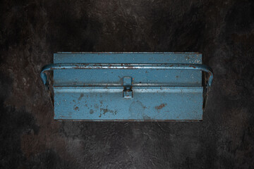 Closed vintage blue metal toolbox on dark surface