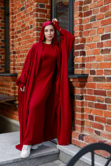 beautiful islamic woman in national dress walking against brick wall	
