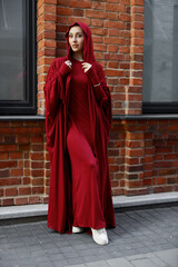 beautiful islamic woman in national dress walking against brick wall	
