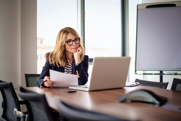 Blond haired business woman using a laptop in a modern office