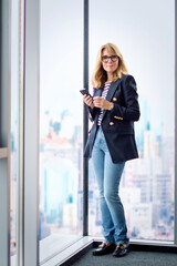 Attractive blond haired woman standing by the window in a modern office