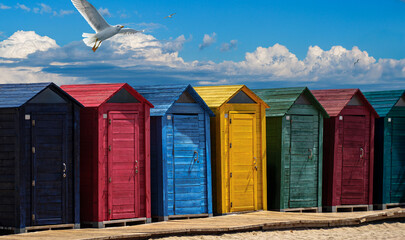Brightly colored beach huts on sandy coast of Spain resort, summer holidays on Mediterranean Sea.