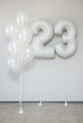white pearlescent balloons with helium in a bunch and white foil numbers 23