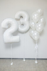 white pearlescent balloons with helium in a bunch and white foil numbers 23