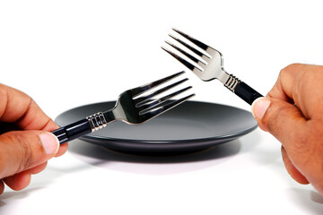hand holding cutlery set above empty plate on white background 