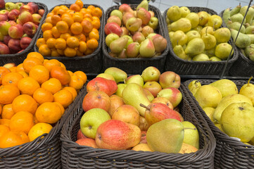Colorful baskets of fresh apples, mandarins, and pears displayed at a market stall