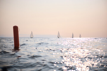 Sailing regatta in the Gulf of Finland at sunset, few sailing yachts competing in a race, splashing...