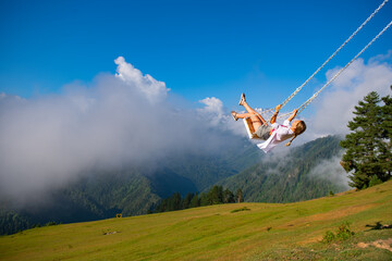 Girl swinging on a swing in the mountains of Georgia in Ushguli