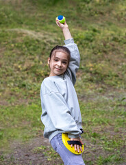 Young girl playing with a foam ball and racket outdoors in a park