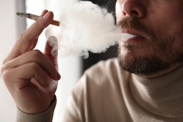 Man smoking cigarette on blurred background, closeup