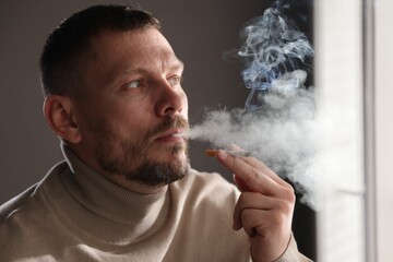 Man smoking cigarette near window in room