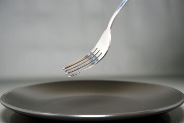 A fork over ceramic plate close-up shot, Selective focused on fork with blurry background 