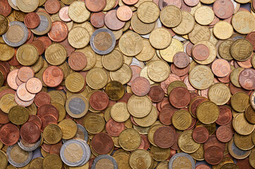 Variety of coins scattered on a surface showing different denominations and colors from various currencies across the world