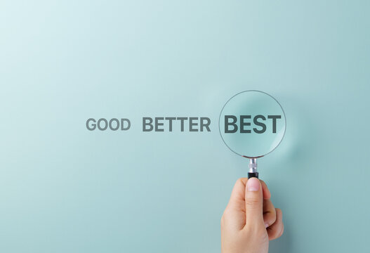 Good Better Best Performance Evaluation Concept. A hand holds magnifying glass over word BEST in sequence reading GOOD BETTER BEST, symbolizing quality improvement, ranking, and performance assessment