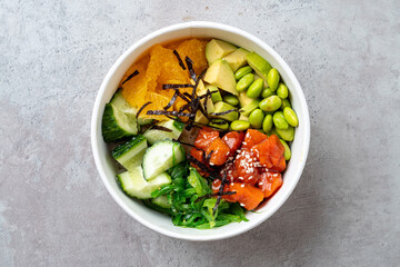 A beautifully arranged sushi bowl features diced salmon, avocado, cucumber, and edamame, complemented by citrus segments and crispy seaweed. A tasty and healthy meal option