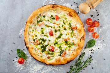 A delectable white pizza emerges from a hot oven, adorned with bright cherry tomatoes and fresh basil. Aromatic herbs and a wooden pepper mill add rustic touch to this culinary masterpiece