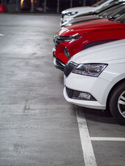 Raw of cars in an underground car park with white and red color vehicle in front. Selective focus. City over crowing problem.