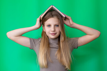 Playful girl balancing book on head. Young girl with long blonde hair playfully holding an open...