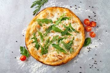 Savory white pizza featuring creamy cheese, vibrant arugula, and ripe cherry tomatoes, arranged artfully on a textured gray surface, evoking a sense of culinary delight