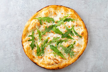 A tantalizing white pizza emerges from the oven, showcasing a golden crust adorned with creamy cheese and vibrant arugula leaves. The dish beckons with its enticing aroma and fresh ingredients