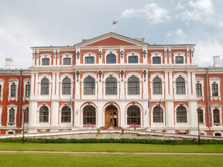 Huge court yard of Jelgava palace with well looked after grass lawn and neat footpaths, blue cloudy sky. Popular city landmark and tourist attraction. Warm sunny day. Latvia travel and tourism.