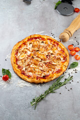 A round, freshly baked pizza rests on a rustic countertop, adorned with vibrant toppings including tomatoes and basil, inviting a delightful meal to share among friends and family
