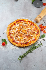 Mouthwatering pizza rests on a lightly floured surface, adorned with golden-brown crust and vibrant toppings of chicken, tomatoes, and herbs. The aroma fills the kitchen, creating a cozy ambiance