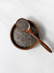 Top view of chia seeds in a wooden bowl with a spoon. Healthy superfood concept, ideal for...