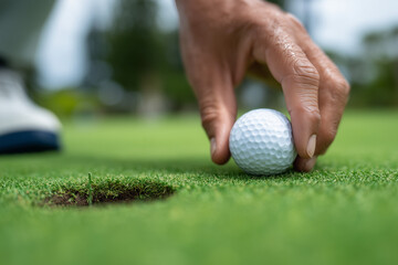 Golfer placing ball near hole