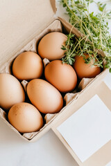 Delivery box filled with farm-fresh eggs and fresh herbs, showcasing a thank-you note with farm logo. Clean neutral setting, concept of local agriculture, farm-to-table dining, wellness