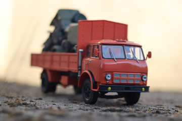 Orange scale model of a Soviet cabover truck carrying SUVs.